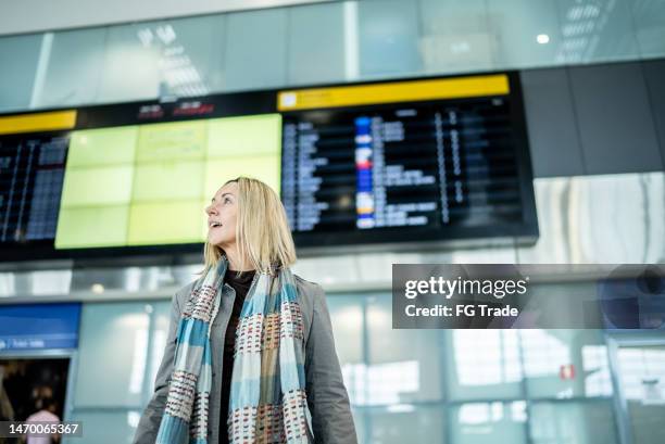 mature woman walking in the airport - woman flying scarf stock pictures, royalty-free photos & images