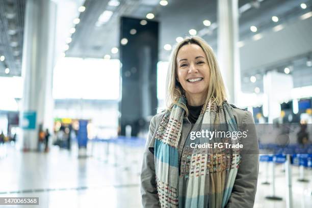 portrait of a happy mature woman in the airport - woman flying scarf stock pictures, royalty-free photos & images