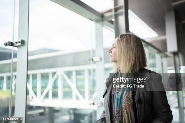 mature woman contemplating in the airport - woman flying scarf stock pictures, royalty-free photos & images