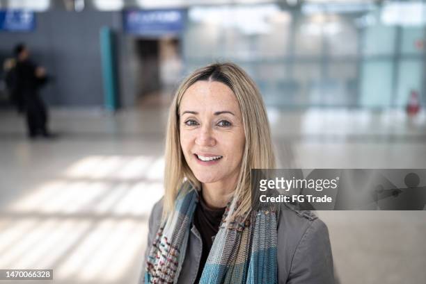 portrait of a mature woman in the airport - woman flying scarf stock pictures, royalty-free photos & images