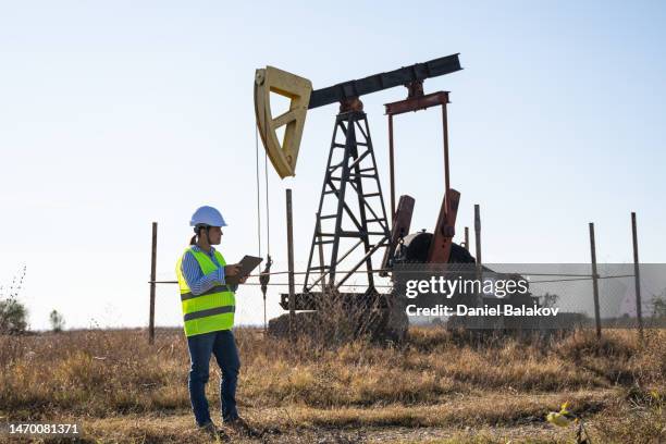 pregnant woman working at oil field with tablet. petroleum engineer. - rigips stock pictures, royalty-free photos & images