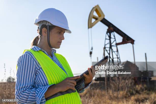 pregnant woman working at oil field with tablet. petroleum engineer. - working oil pumps stock pictures, royalty-free photos & images