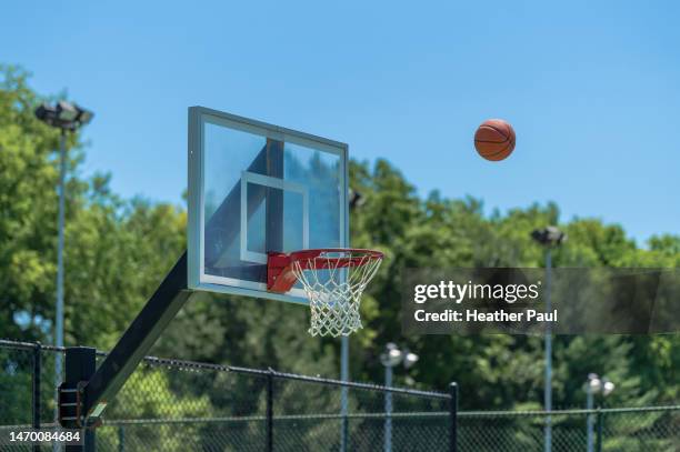 basketball in the air after being shot towards a basketball hoop on a playground or court - shooting baskets stock pictures, royalty-free photos & images