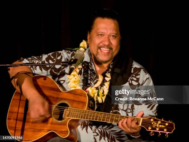 Singer/songwriter/musician Willie Kahaiali'i plays guitar and sings at a fundraiser for Hanalei School, wearing a yellow plumeria lei created by Lei...