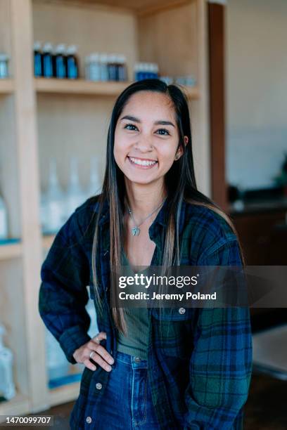 portrait of a cheerful college age woman standing and smiling in zero waste store - different nationalities stockfoto's en -beelden