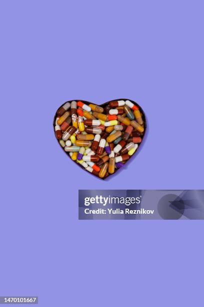 pills in shape of heart of purple background - health and safety icons stock pictures, royalty-free photos & images