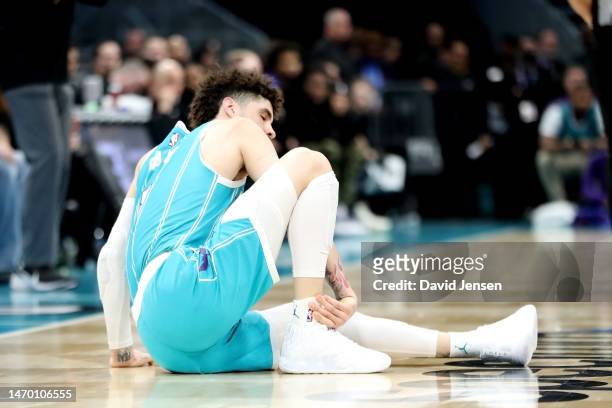 LaMelo Ball of the Charlotte Hornets holds his ankle after an apparent injury during the second half of a basketball game against the Detroit Pistons...