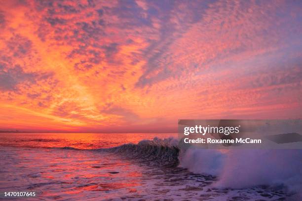 The rising sun lights the clouds as a wave breaks in Santa Monica Bay in 2012 in Malibu, California.