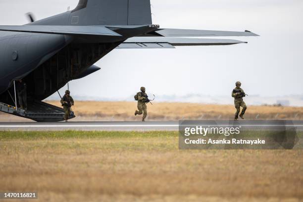 Australian Defence Force personnel run out of the back of a RAAF C-130J Hercules to perform tactical exercises during a Australian Defence Force...