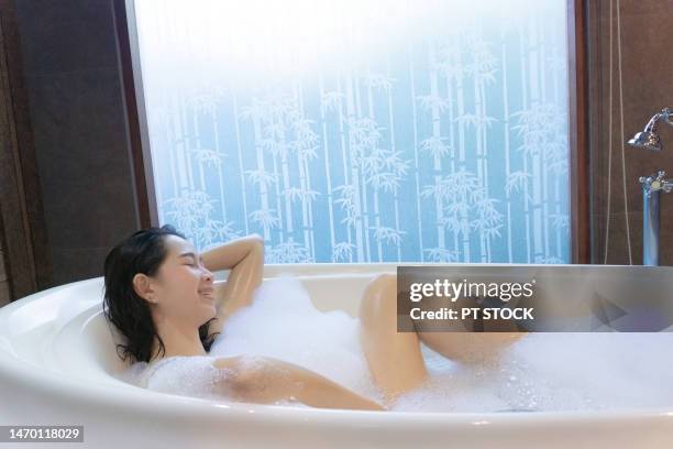 a woman is scrubbing herself in the bathtub. - woman shower candle stock-fotos und bilder