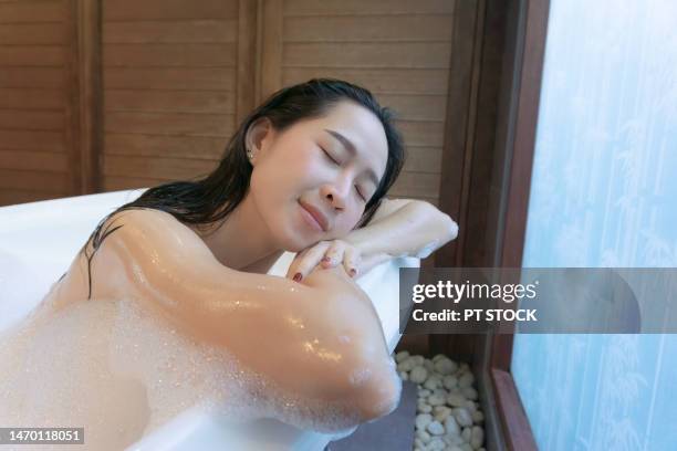 a woman is scrubbing herself in the bathtub. - woman shower candle stock-fotos und bilder