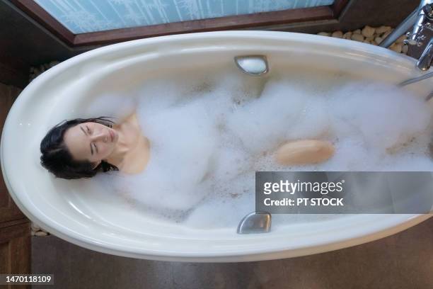 a woman is scrubbing herself in the bathtub. - woman shower candle stock-fotos und bilder