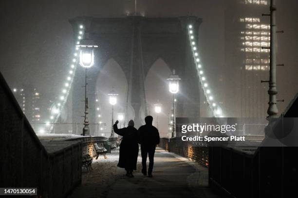 People walk across the Brooklyn Bridge during a storm on February 27, 2023 in New York City. Parts of northern New York City could see up to five...