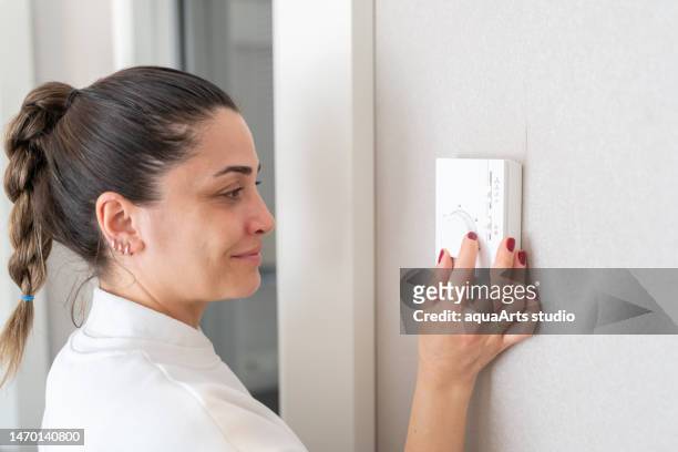 the woman who adjusts the room temperature from the air conditioning panel - fahrenheit imagens e fotografias de stock