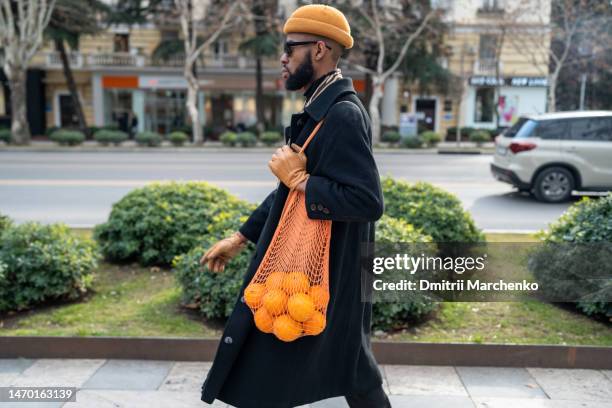 african american walking city street carrying oranges in reusable cotton mesh shopping bag - menschen vor laden stock-fotos und bilder