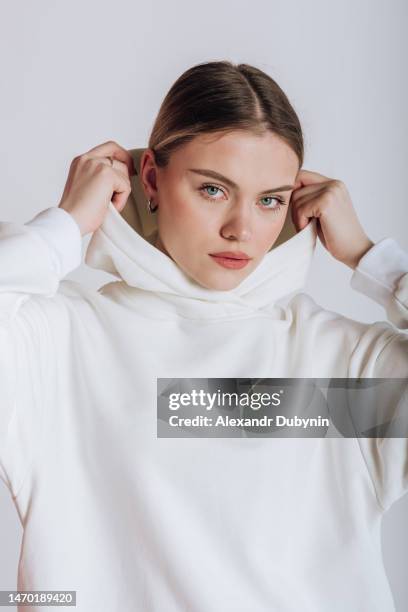 portrait of a female model in a hoodie on a white background - camisa con capucha fotografías e imágenes de stock