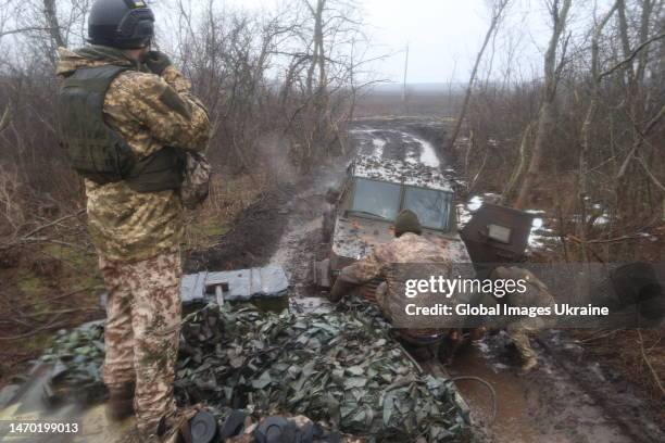 Ukrainian military members attach a wire rope to a pickup truck bogged down in the mud to tow it away on February 26, 2023 in Donetsk Oblast,...