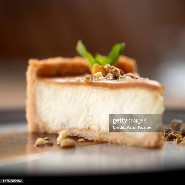 cheesecake with caramel. piece of dessert sprinkled with nuts and decorated with mint on plate. sweets with salted caramel. sectional side view. close-up. soft focus - cheesecake stock pictures, royalty-free photos & images