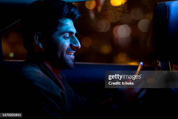 happy man using mobile phone on back seat of car - indian ethnicity man car stock pictures, royalty-free photos & images