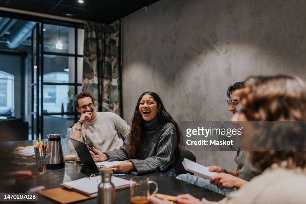 cheerful multiracial colleagues discussing at conference table in board room - entrepreneur stockfoto's en -beelden