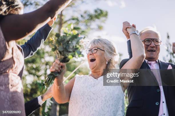 cheerful newlywed senior couple holding hands while dancing with family on wedding day - old couple dancing stock pictures, royalty-free photos & images