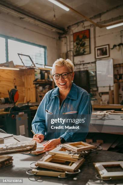 portrait of happy senior female carpenter at repair shop - schreiner stock-fotos und bilder