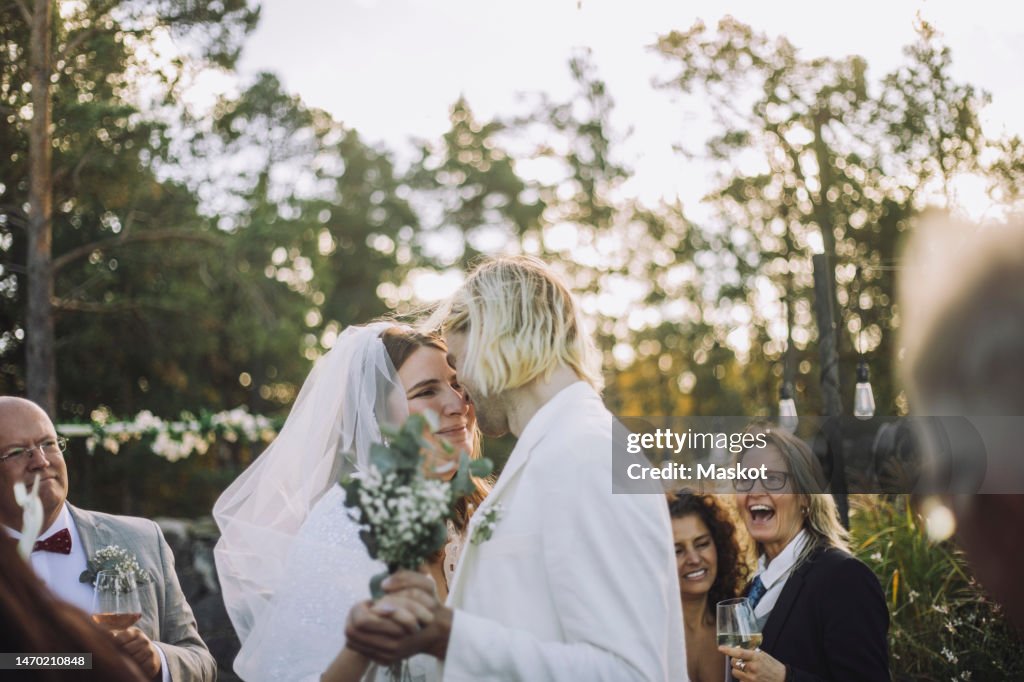 Happy bride and groom dancing together amidst guests during wedding ceremony
