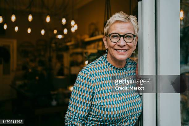 portrait of senior female owner standing at entrance of store - 65 stock pictures, royalty-free photos & images