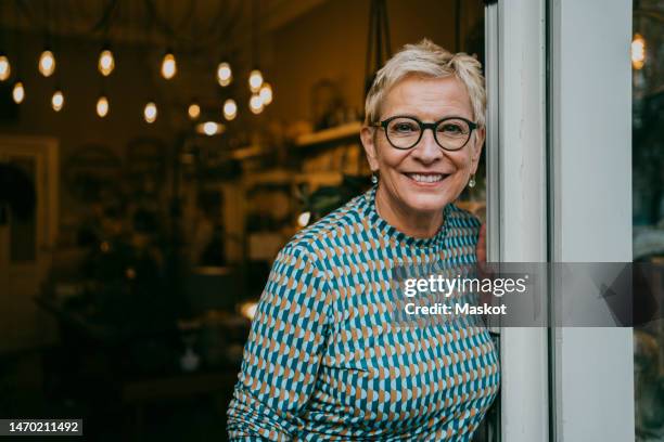 portrait of senior female owner standing at entrance of store - 2022 65 69 stock pictures, royalty-free photos & images