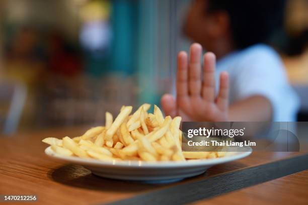 overweight boy rejecting unhealthy food potato fries - transvet stockfoto's en -beelden