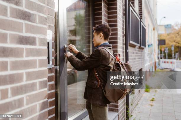 man wearing backpack while locking apartment door - front door lock stock pictures, royalty-free photos & images