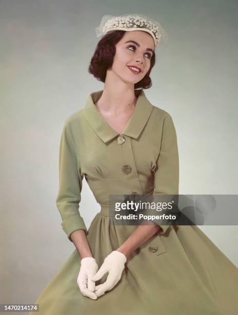 Posed studio portrait of a woman wearing a pale green dress with three quarter length sleeves, a fitted bodice with tucks and a wide, full skirt,...
