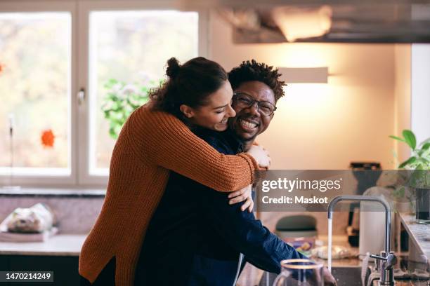 side view of happy woman embracing man washing hands in kitchen at home - 水喉水 個照片及圖片檔