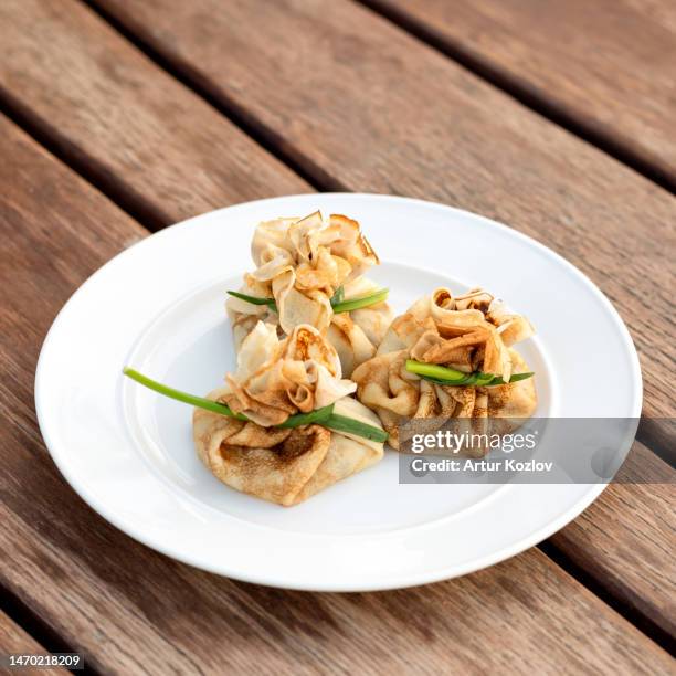 bags of pancakes with stuffing. three pancakes on white plate on wooden table. eastern european cuisine. cold appetizers. flour products. wooden background. view from above. soft focus. copy space - maslenitsa stock pictures, royalty-free photos & images