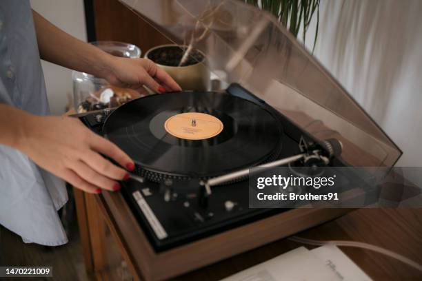 primer plano de una mujer tocando un disco de vinilo en un tocadiscos - lp fotografías e imágenes de stock