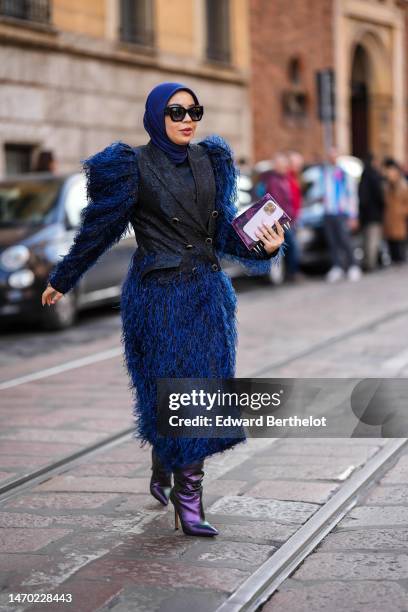 Guest wears black sunglasses, a navy blue scarf as a headband, a navy blue fluffy shoulder pads / long sleeves / long dress, a black denim sleeveless...