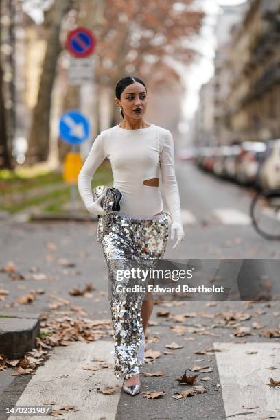 Guest wears crystals large earrings, a silver pendant necklace, a white cut-out chest / long sleeves body, white shiny leather high gloves, a silver...