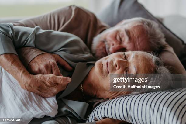 front view of senior couple lying in bed and sleeping. - old bed stockfoto's en -beelden