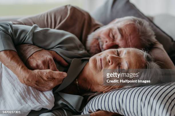 front view of senior couple lying in bed and sleeping. - couple sleeping 個照片及圖片檔