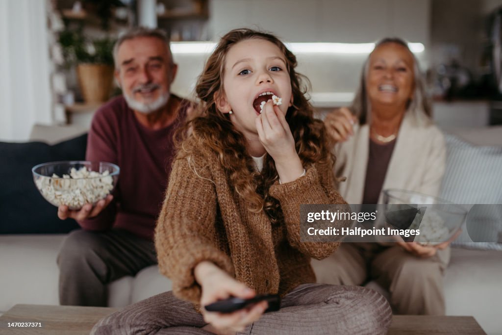 Grandparents watching TV with their granddaughter.