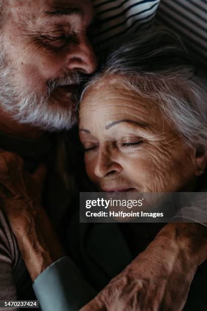 high angle view of senior couple in love,  lying in a bed. - man and woman kissing in bed stock pictures, royalty-free photos & images