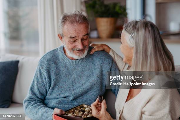 senior couple having nice time together, eating chocolate. - chocolate eating ストックフォトと画像