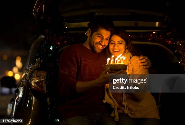couple joyeux célébrant son anniversaire avec un gâteau dans le coffre de la voiture - indian birthday images photos et images de collection