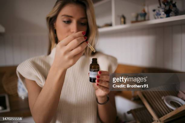 mujer tomando aceite de cannabis para aliviar el estrés en casa - cannabis oil fotografías e imágenes de stock