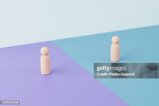 two wooden figurines opposing each other - sich duellieren stock-fotos und bilder