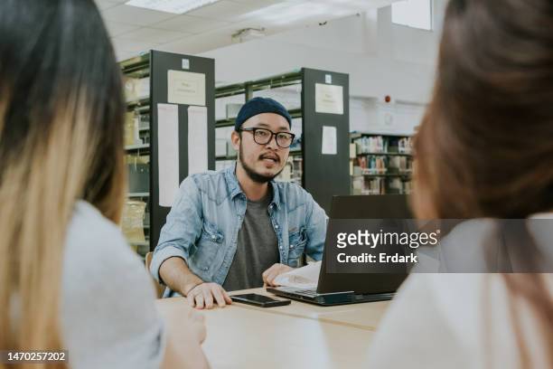 hipster professor talking about his experience working and sharing the knowledge to teenagers in library discussion with tutor lecturer - results show stockfoto's en -beelden