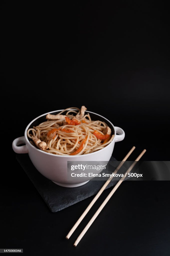 Wheat noodles with chicken and soy sauce in Japanese in a white bowl on a black background