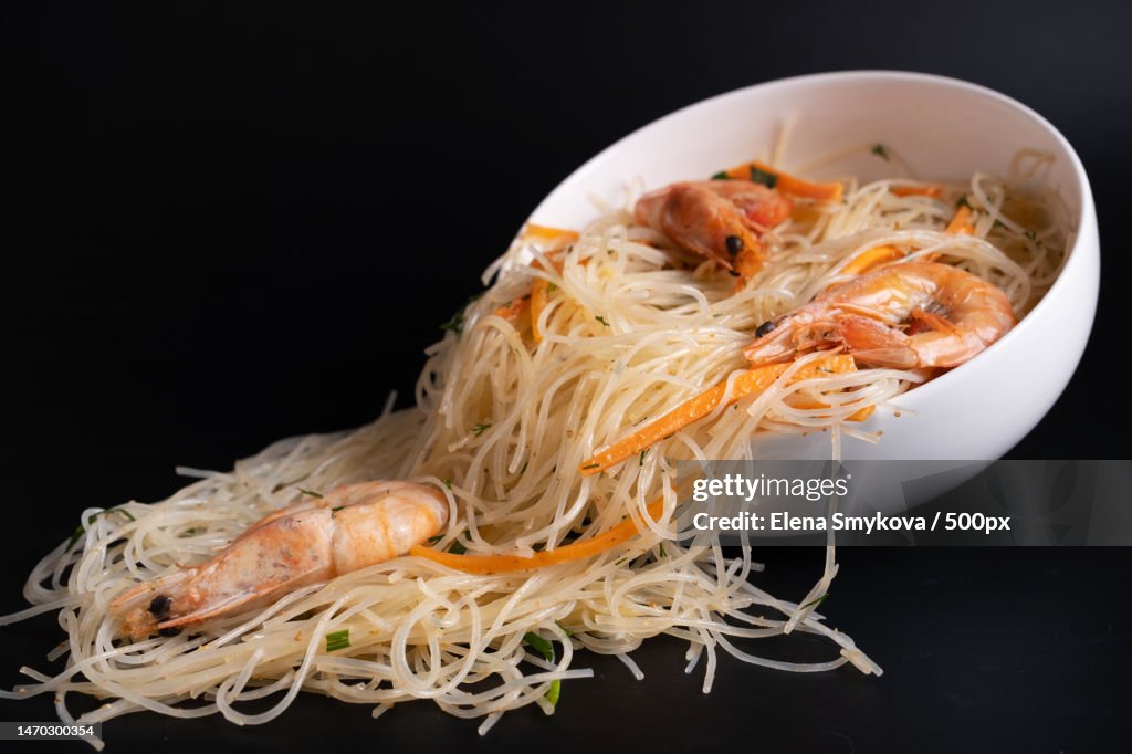 Funchosa salad falls out of a white bowl on a black background,Moscow,Russia