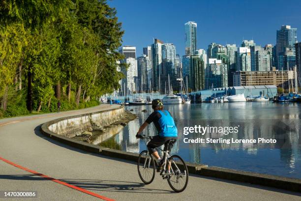 bike riding on the sea wall of downtown vancouver stanley park - vancouver city stock pictures, royalty-free photos & images