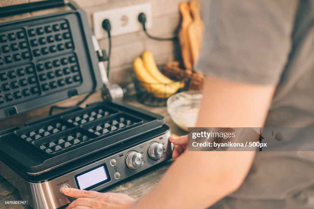 Young woman includes waffle iron,Preparing Belgian waffles in the kitchen Cooking process,Kazakhstan